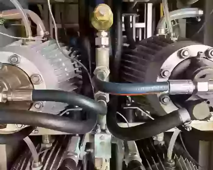 Corroded capillary pipes connected to the pressure manifold on a Nilfisk Delta Booster multi-pump pressure washer before replacement.